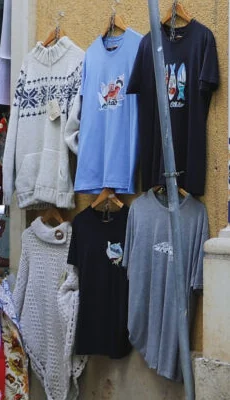 Camisolas de malha e t-shirts com desenhos penduradas à porta da loja